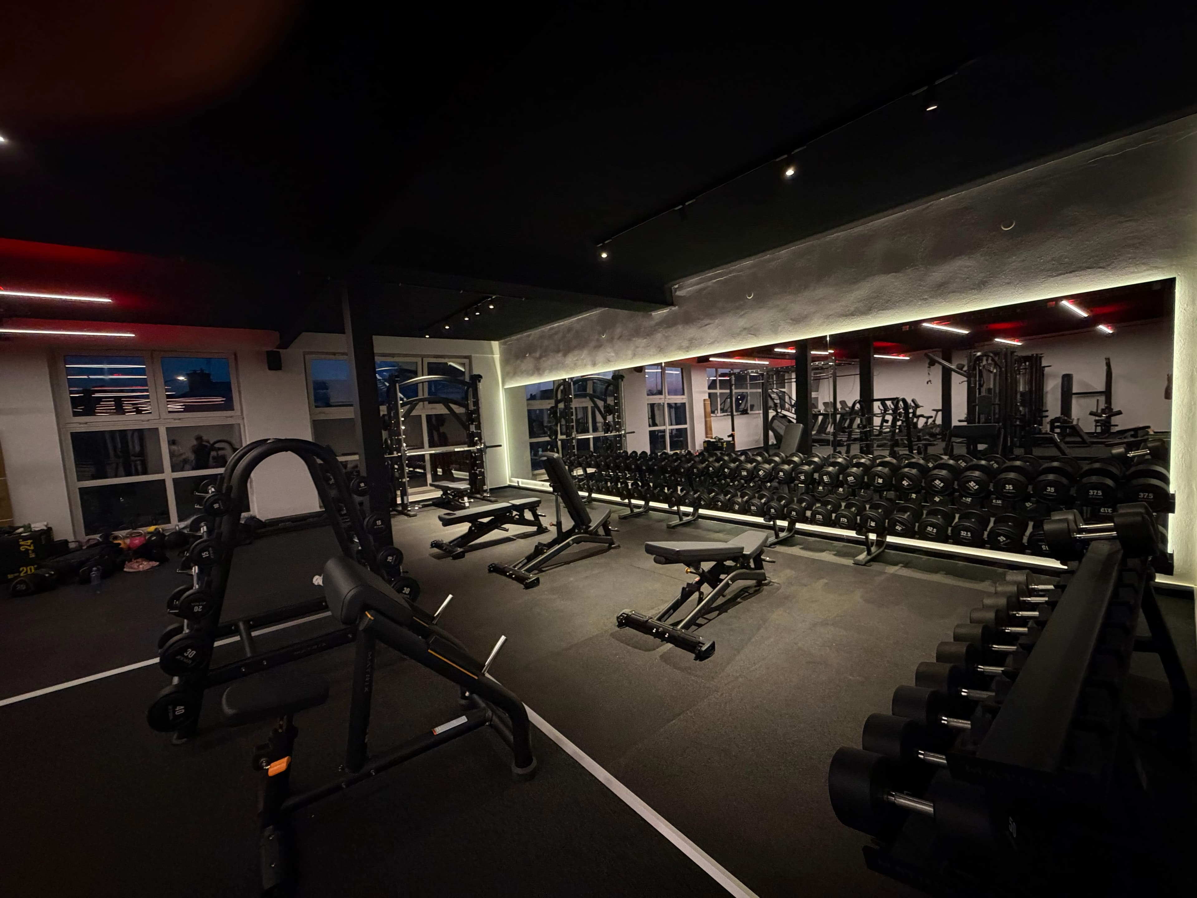 Posilovna NEXT LEVEL GYM – volná váha, lavice a stojan na dřepy s červeným podsvícením stropu