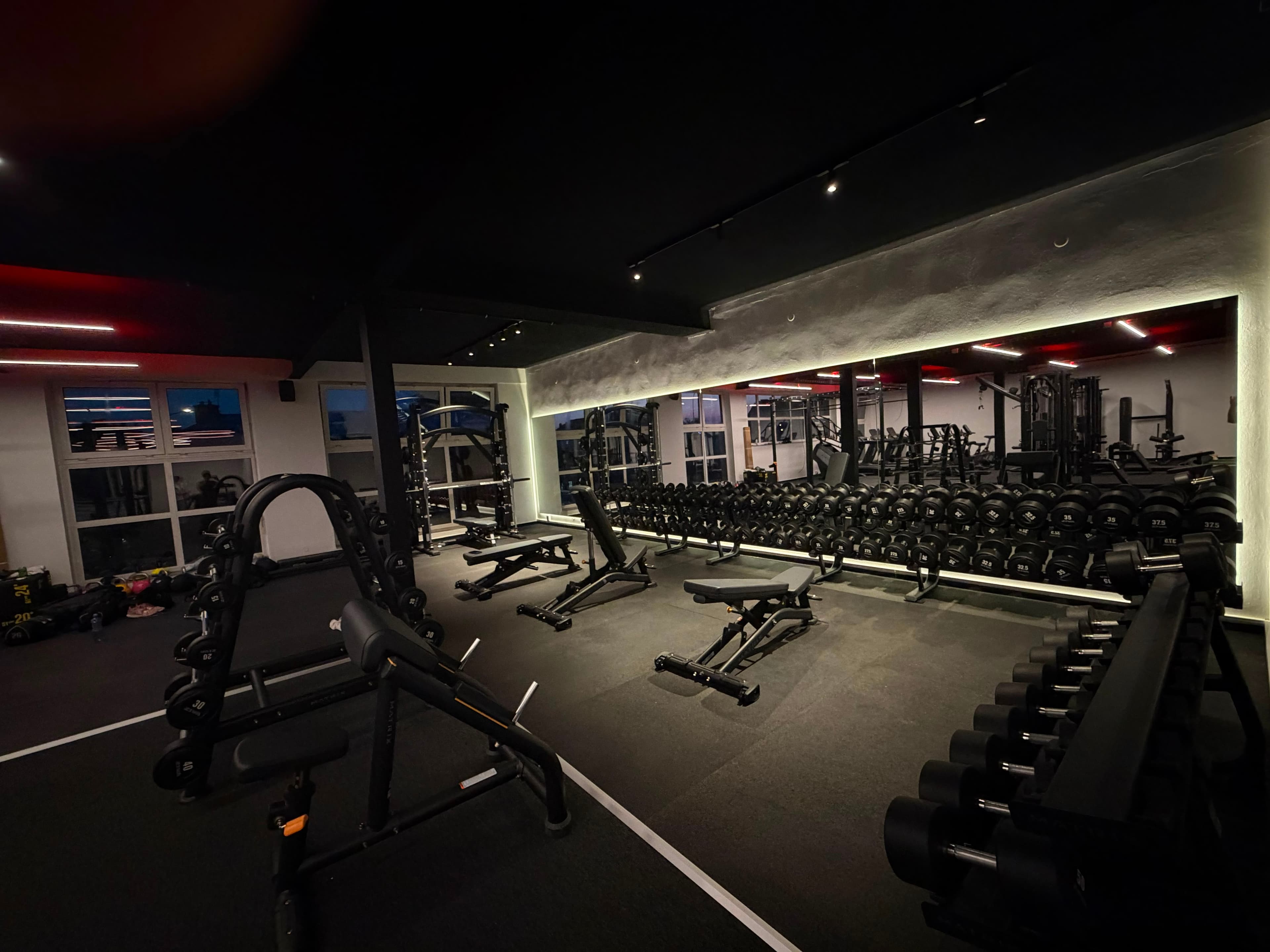 Posilovna NEXT LEVEL GYM – detail stojanu s činkami s červeným podsvícením